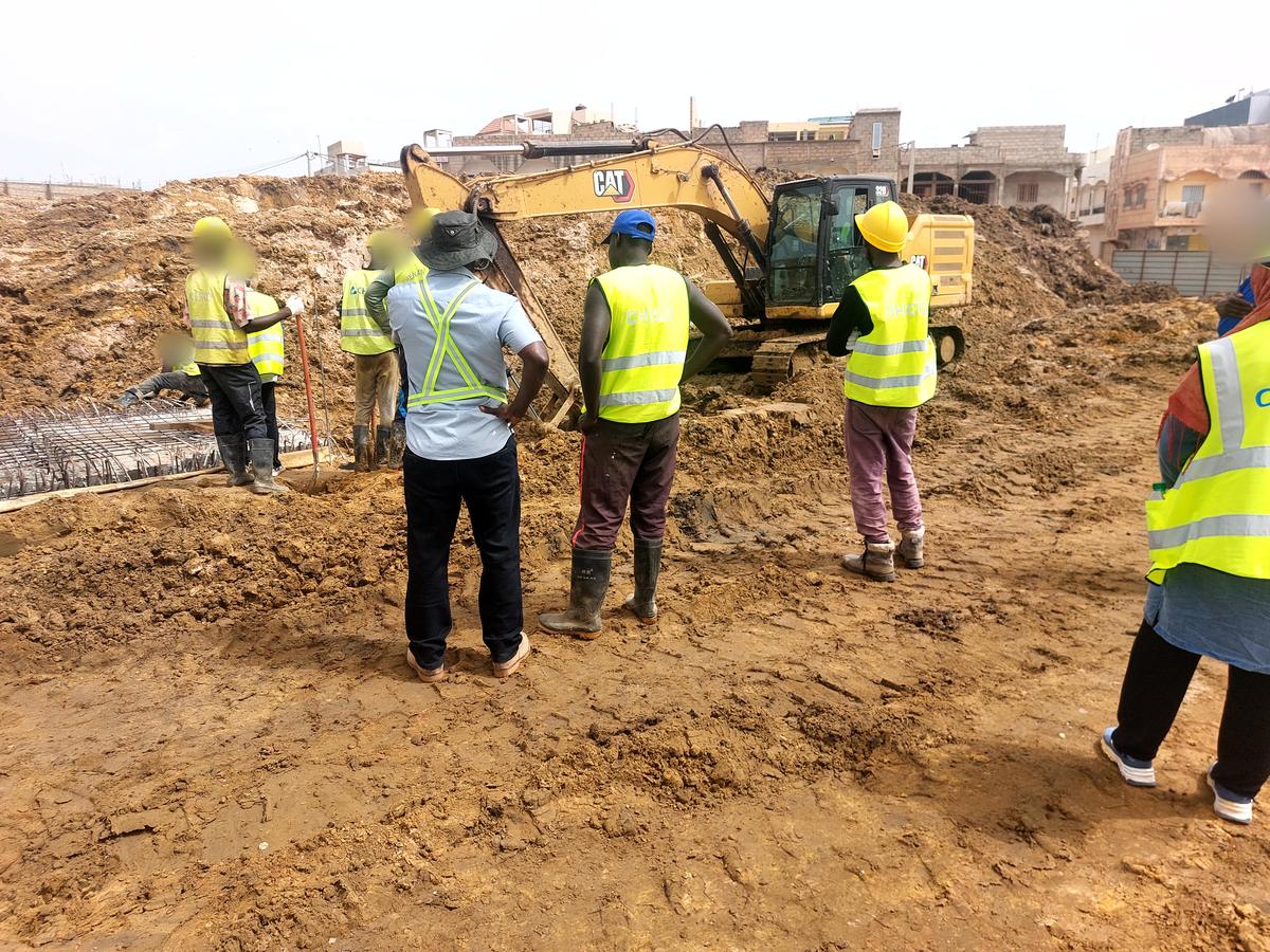 Team in safety vests in front of an excavator on a works site